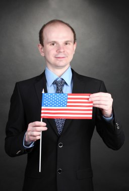 Businessman holding American flag on black background clipart