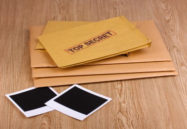 Envelopes with top secret stamp with photo papers on wooden background clipart