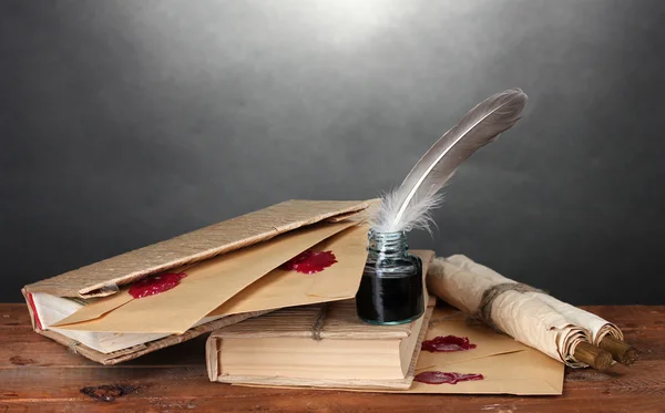 stock image Old books, scrolls, feather pen and inkwell on wooden table on grey background