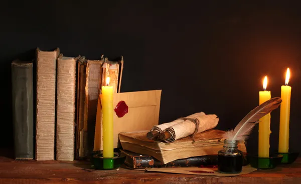Vecchi libri, pergamene, calamaio penna piuma e candele su tavolo di legno su sfondo marrone — Foto Stock