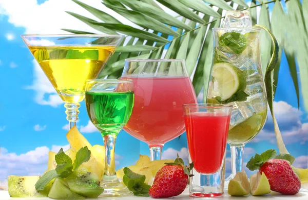 Glazen cocktails op tabel op blauwe hemelachtergrond — Stockfoto