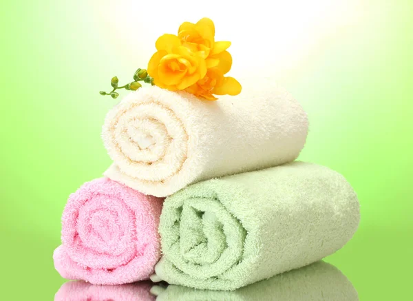 Bunte Handtücher und Blumen auf grün-gelbem Hintergrund — Stockfoto