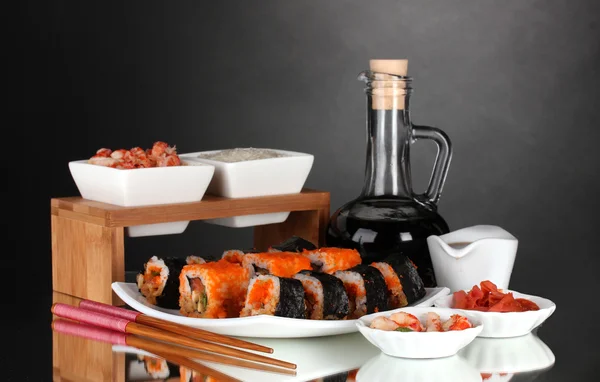 Heerlijke sushi op plaat, eetstokjes, sojasaus, vis en garnalen op grijze achtergrond — Stockfoto