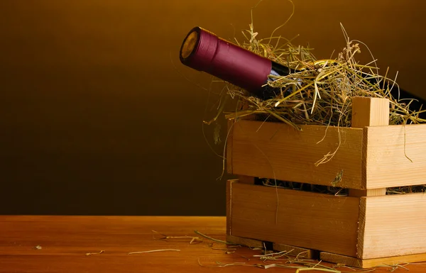 Flaska bra vin i låda på träbord på brun bakgrund — Stockfoto