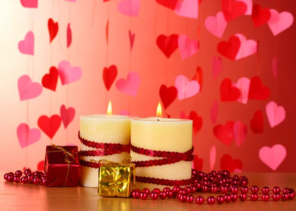 Όμορφα κεριά με ρομαντική διακόσμηση σε ένα ξύλινο τραπέζι σε κόκκινο φόντο — Φωτογραφία Αρχείου