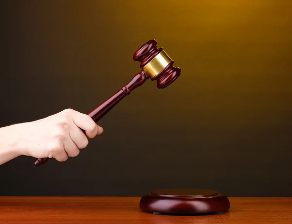 Martelo do juiz na mão sobre fundo marrom — Fotografia de Stock