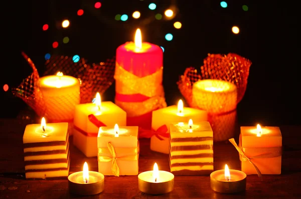 Maravilhosas velas na mesa de madeira no fundo brilhante — Fotografia de Stock