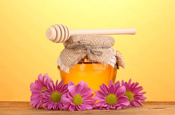 Miel dulce en tarro con rociador sobre mesa de madera sobre fondo amarillo — Foto de Stock