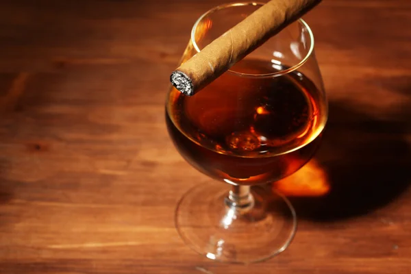 Bicchiere di brandy e sigaro sul tavolo di legno — Foto Stock