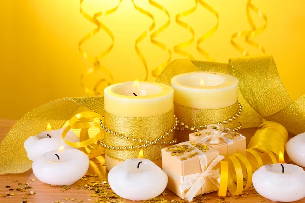Beautiful candles, gifts and decor on wooden table on yellow background Royalty Free Stock Photos