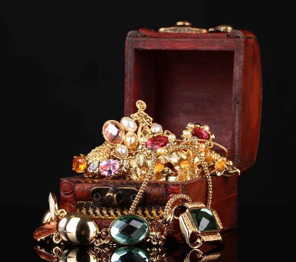 Caixa de madeira cheia de jóias de ouro no fundo preto — Fotografia de Stock