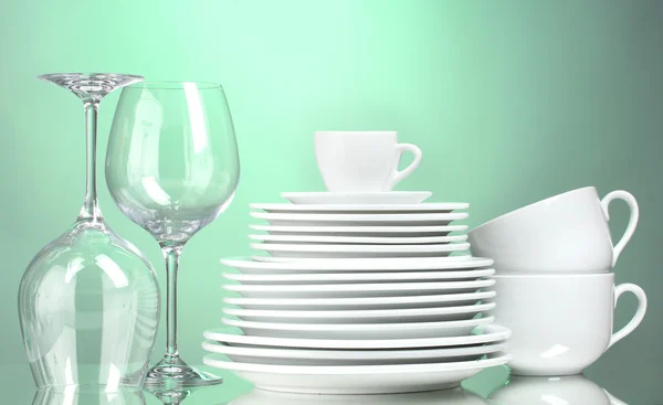 Чистые тарелки, чашки и стаканы на зеленом фоне — стоковое фото