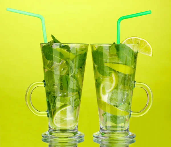 Glasses of cocktail with lime and mint on green background — Stock Photo, Image