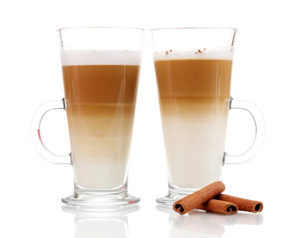 Latte aux saveurs parfumées dans des tasses en verre et cannelle isolées sur du blanc — Photo