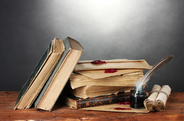 古い本、巻物、羽ペン、灰色の背景上の木製のテーブルの上のインクつぼ — ストック写真