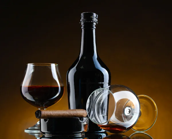 Μπουκάλι και δοχεία του κονιάκ και πούρο σε καφέ φόντο — Φωτογραφία Αρχείου
