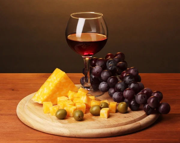 Vino en vino y queso sobre mesa de madera sobre fondo marrón — Foto de Stock