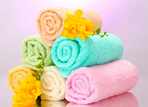 Asciugamani colorati e fiori su sfondo viola — Foto Stock