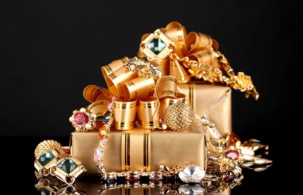 Verschiedene Goldschmuck und Geschenke auf schwarzem Hintergrund — Stockfoto