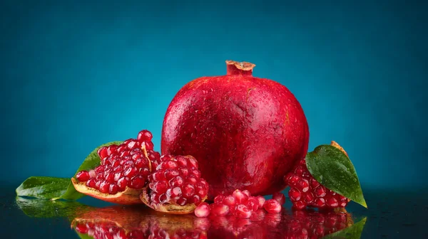 Zralé granátové jablko ovoce s listy na modrém pozadí — Stock fotografie