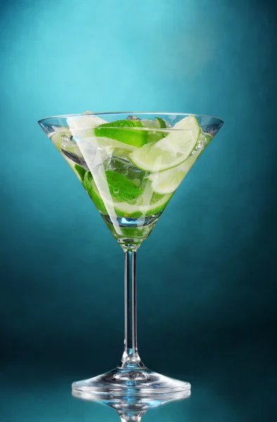 Glass of cocktail with lime and mint on blue background — Stock Photo, Image