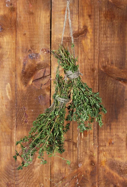 Tomillo verde fresco colgado en la cuerda sobre fondo de madera — Foto de Stock