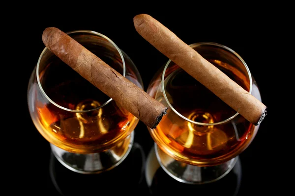 Dwie szklanki z brandy i cygar na czarnym tle — Zdjęcie stockowe