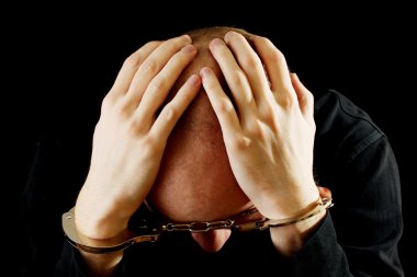 Repentant bandit in handcuffs isolated on black clipart