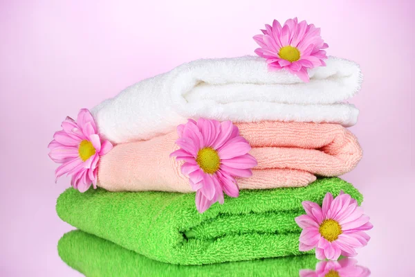 Toallas y hermosas flores sobre fondo rosa —  Fotos de Stock