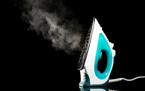 Electric iron with steam on black — Stock Photo, Image
