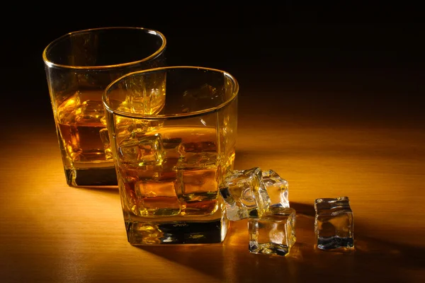 スコッチ ウイスキーや木製のテーブルの上の氷の 2 つのメガネ — ストック写真