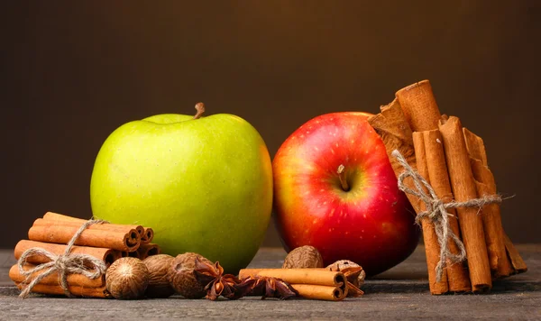 Tyčinky skořice, jablka, muškátový oříšek a anýzu na dřevěný stůl na hnědé pozadí — Stock fotografie
