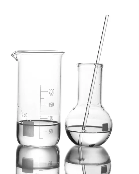 Béquer de medição e frasco com água e com reflexão isolada sobre branco — Fotografia de Stock