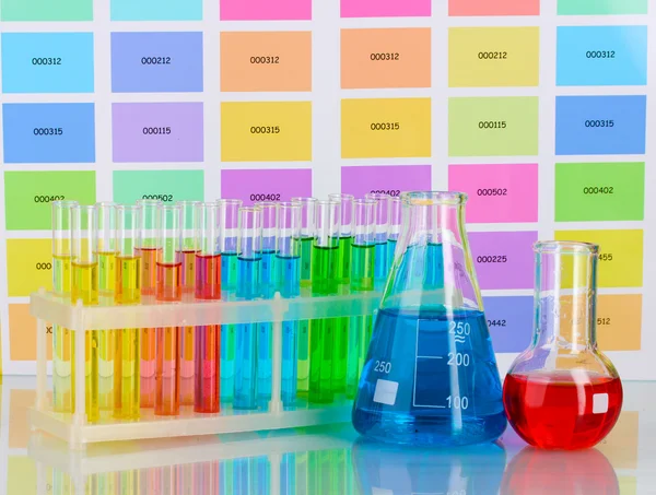 Test-tubes and flasks with color liquid on color samples background — Stock Photo, Image