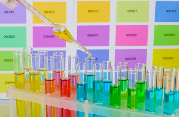 Tubos de ensayo con líquido de color y pipeta sobre fondo de muestras de color —  Fotos de Stock