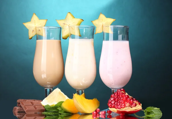 Молочные коктейли с фруктами и шоколадом на деревянном столе на синем фоне — стоковое фото