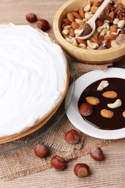 Kuchen auf Glasständer und Nüsse auf Holztisch — Stockfoto