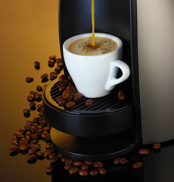Máquina de café expreso vertiendo café en taza sobre fondo marrón — Foto de Stock