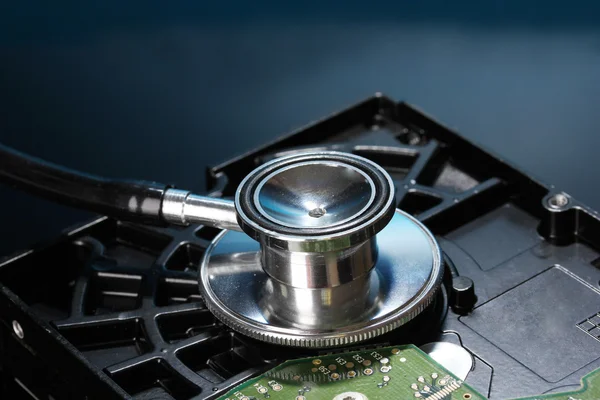 Stethoscope on hard disk drive on dark blue background — Stock Photo, Image