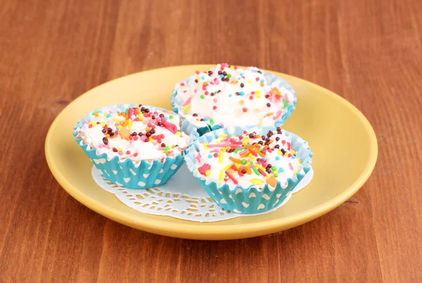 Cupcake cremosi su piattino su sfondo di legno — Foto Stock
