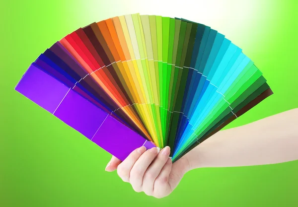 Kezében fényes paletta színek, zöld háttér — Stock Fotó