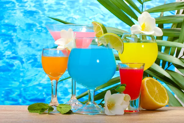 Exotické koktejly a květiny na stole na pozadí modré moře — Stock fotografie
