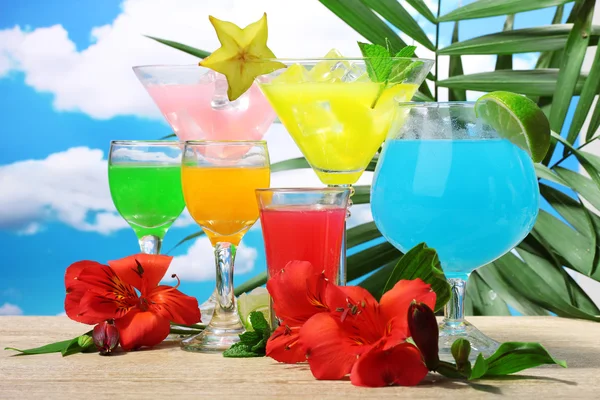 Экзотические коктейли и цветы на синем фоне неба — стоковое фото
