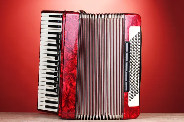 Retro accordion on wooden table on red background — Stock Photo, Image