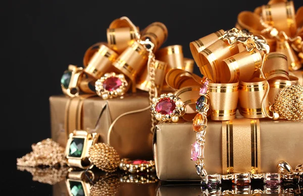 Varias joyas de oro y regalos sobre fondo negro —  Fotos de Stock