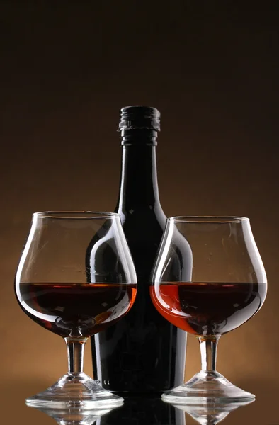 Brýle brandy a láhev na hnědé pozadí — Stock fotografie