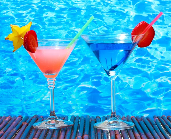 Glasses of cocktails on table on blue sea background — Stock Photo, Image
