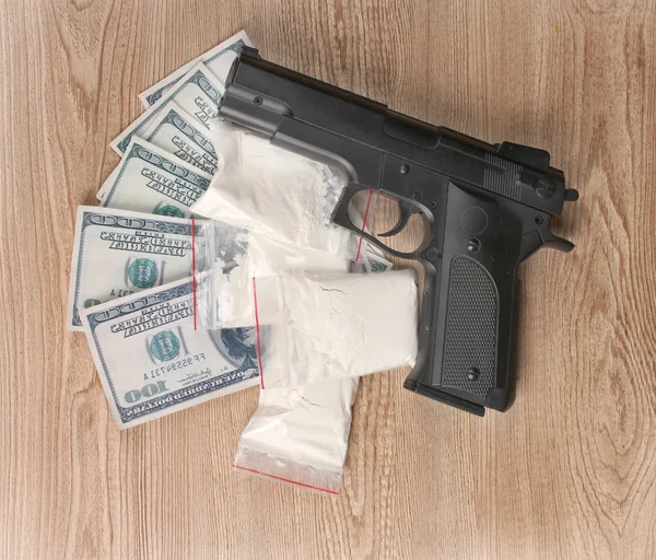 Kokain v obalech, dolary a pistole na dřevěné pozadí — Stock fotografie