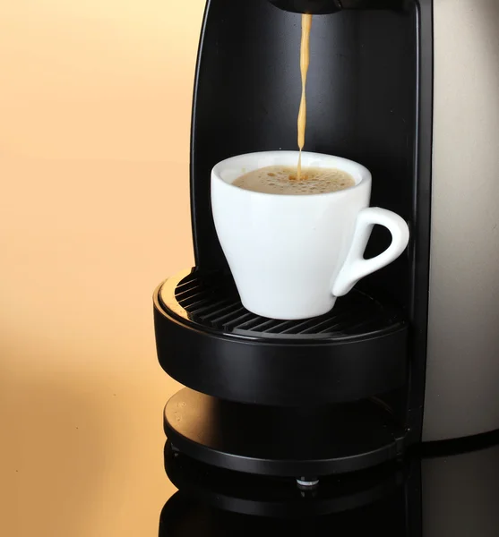 Macchina da caffè espresso versando caffè in tazza su sfondo marrone — Foto Stock