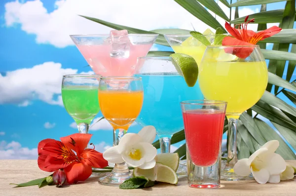 Exotische cocktails en bloemen op tafel op blauwe hemelachtergrond — Stockfoto
